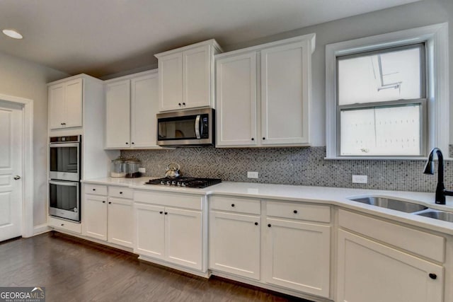 kitchen featuring sink, backsplash, white cabinets, and appliances with stainless steel finishes