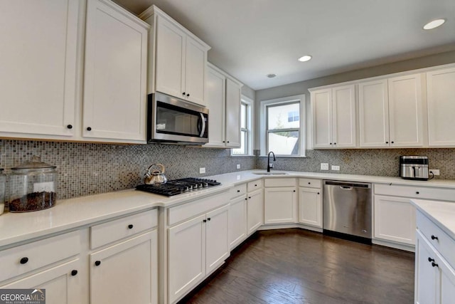 kitchen with tasteful backsplash, white cabinets, sink, dark hardwood / wood-style flooring, and stainless steel appliances