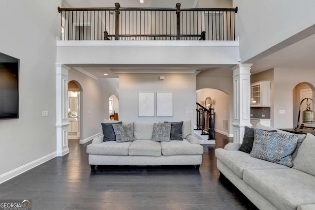 living room featuring ornamental molding, dark wood-type flooring, a high ceiling, and ornate columns