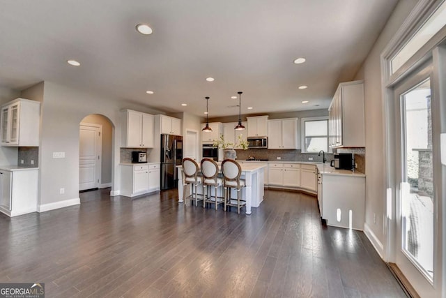 kitchen featuring appliances with stainless steel finishes, a center island, decorative light fixtures, white cabinetry, and a breakfast bar area