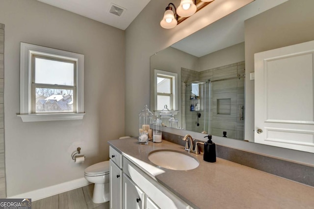 bathroom with toilet, a shower with door, and vanity