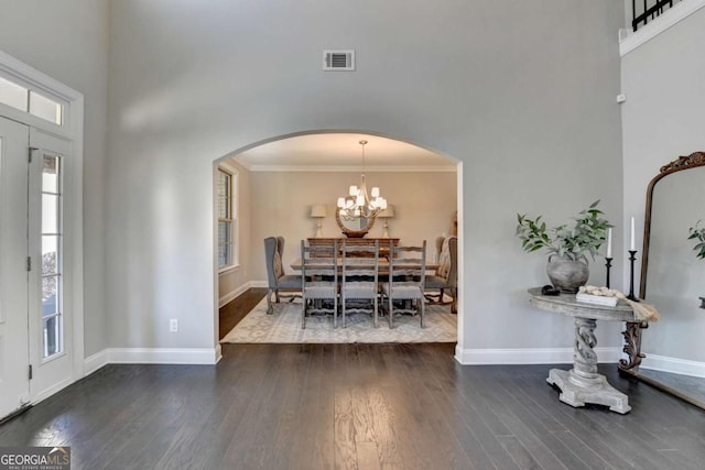 dining room featuring a chandelier, a high ceiling, crown molding, and dark hardwood / wood-style flooring