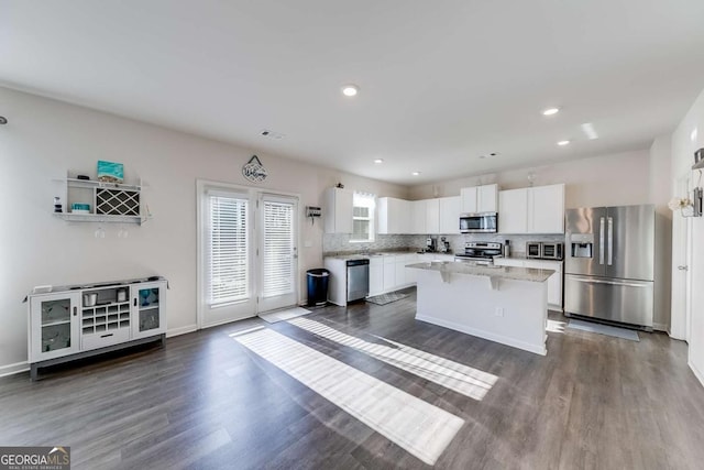 kitchen featuring a center island, light stone countertops, white cabinets, stainless steel appliances, and dark hardwood / wood-style floors