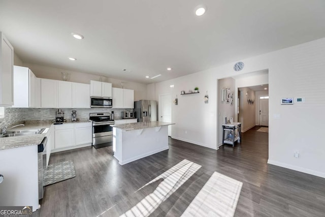 kitchen with appliances with stainless steel finishes, a center island, white cabinetry, tasteful backsplash, and sink