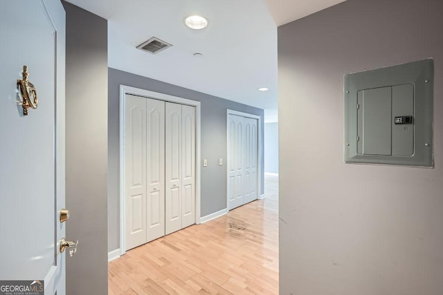 hallway with electric panel and light wood-type flooring