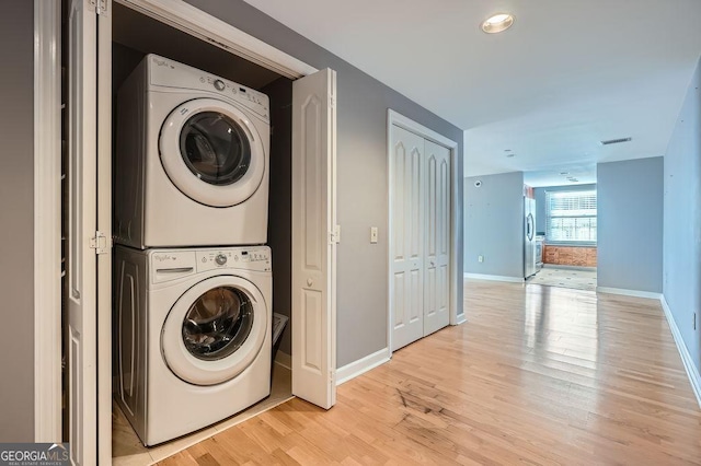 washroom with light hardwood / wood-style flooring and stacked washer and dryer