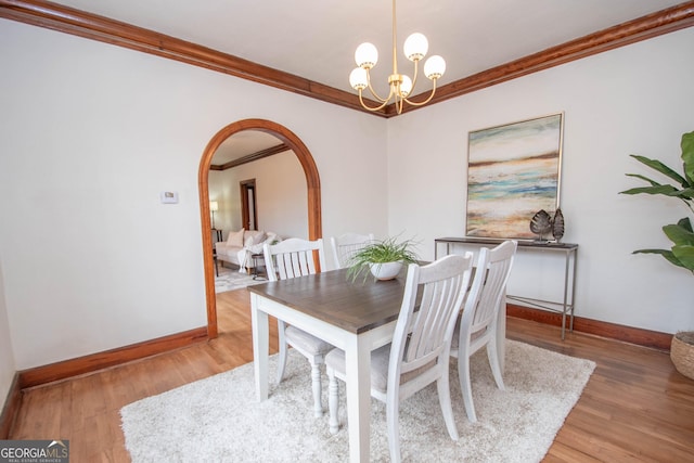 dining area featuring light hardwood / wood-style flooring, ornamental molding, and a notable chandelier