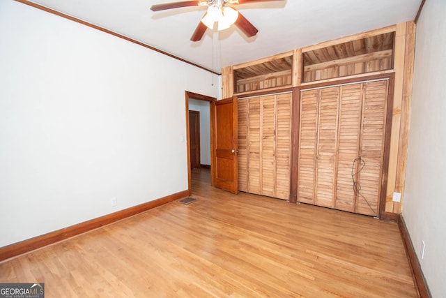 unfurnished bedroom with multiple closets, ceiling fan, light hardwood / wood-style flooring, and crown molding