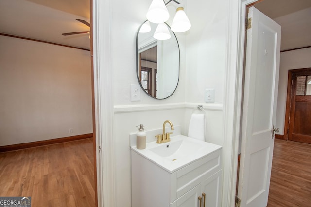 bathroom with wood-type flooring, crown molding, ceiling fan, and vanity