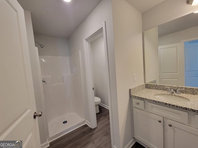 bathroom featuring a shower, hardwood / wood-style flooring, vanity, and toilet