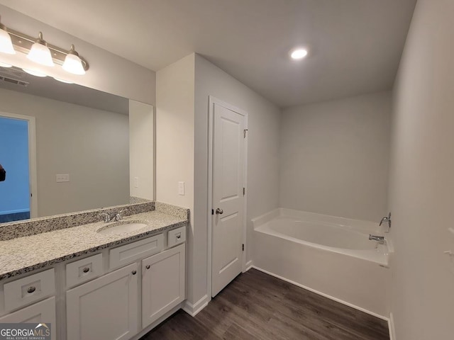 bathroom featuring vanity, wood-type flooring, and a tub