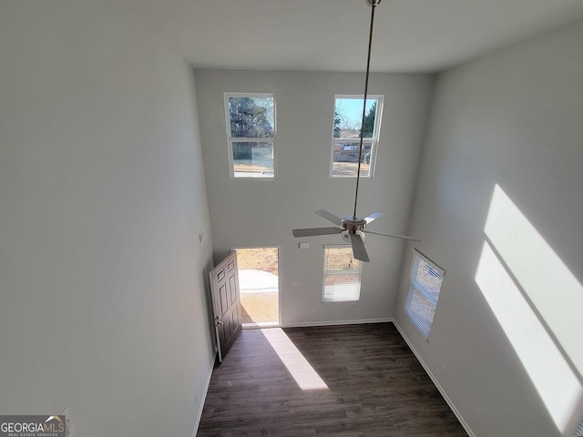 interior space with ceiling fan, a towering ceiling, dark hardwood / wood-style flooring, and a wealth of natural light