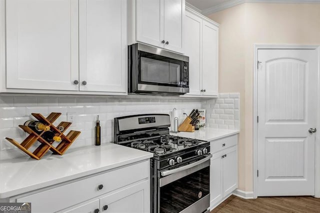 kitchen featuring backsplash, white cabinetry, dark wood-type flooring, ornamental molding, and stainless steel appliances