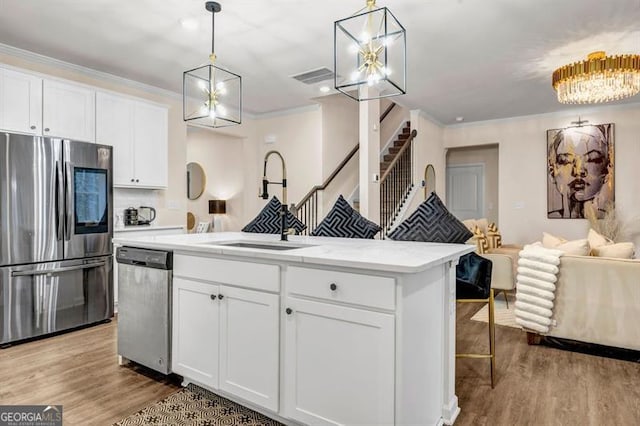 kitchen with white cabinets, a kitchen island with sink, hanging light fixtures, and appliances with stainless steel finishes