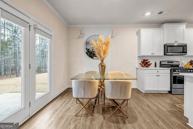 dining room with light hardwood / wood-style flooring and ornamental molding