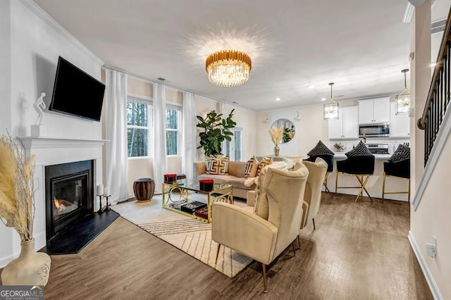 living room with a notable chandelier, hardwood / wood-style flooring, and ornamental molding