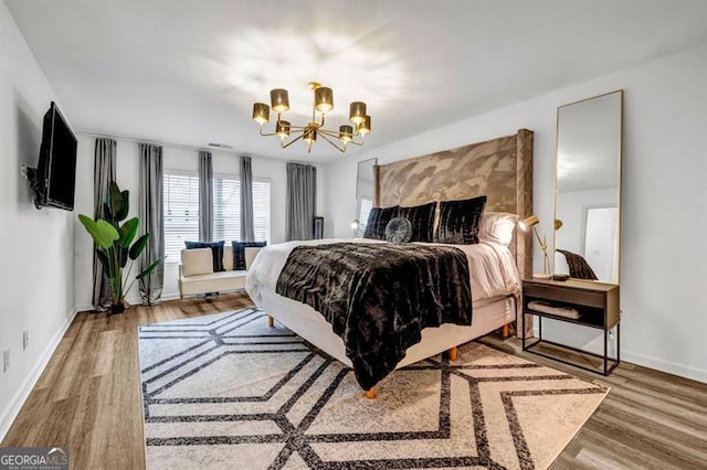 bedroom featuring wood-type flooring and an inviting chandelier