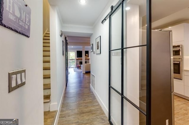 corridor featuring ornamental molding and light wood-type flooring