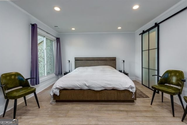 bedroom featuring crown molding, a barn door, and light hardwood / wood-style floors