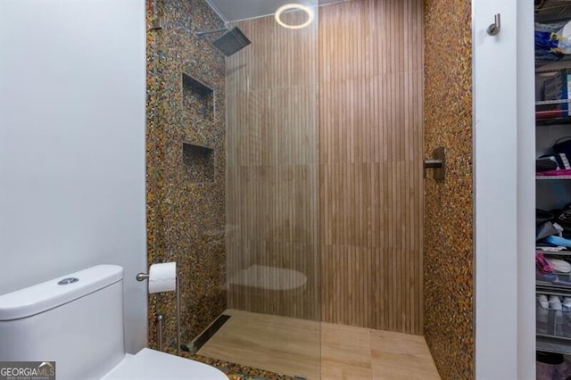 bathroom with tiled shower and toilet