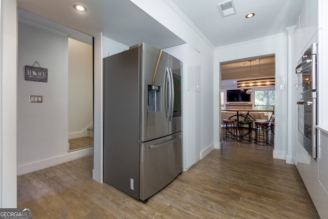 kitchen with stainless steel appliances, crown molding, hardwood / wood-style flooring, and white cabinetry