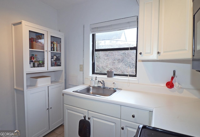 kitchen with sink, white cabinets, range, and light tile patterned floors