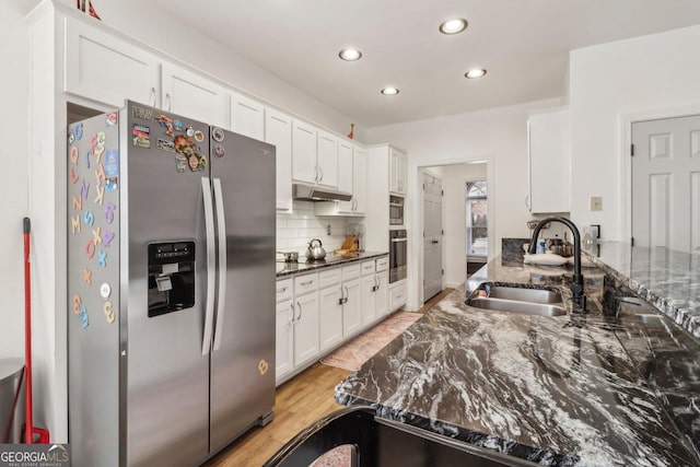 kitchen with appliances with stainless steel finishes, tasteful backsplash, sink, white cabinets, and dark stone counters