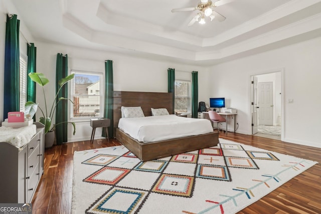 bedroom featuring ceiling fan, a raised ceiling, ornamental molding, and dark hardwood / wood-style floors