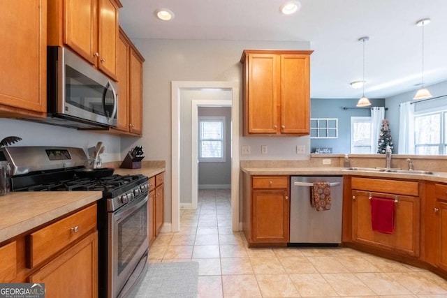 kitchen featuring hanging light fixtures, a healthy amount of sunlight, appliances with stainless steel finishes, and sink