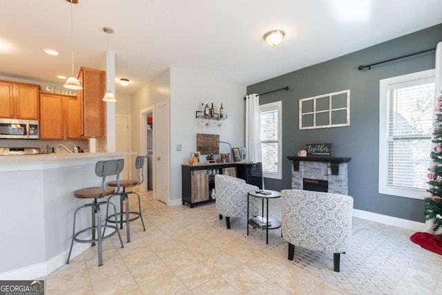 interior space featuring pendant lighting, a fireplace, a breakfast bar, and a wealth of natural light