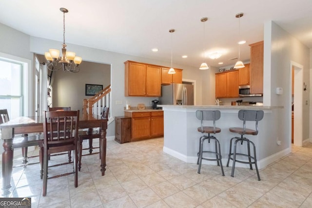 kitchen with a breakfast bar, appliances with stainless steel finishes, an inviting chandelier, decorative light fixtures, and kitchen peninsula