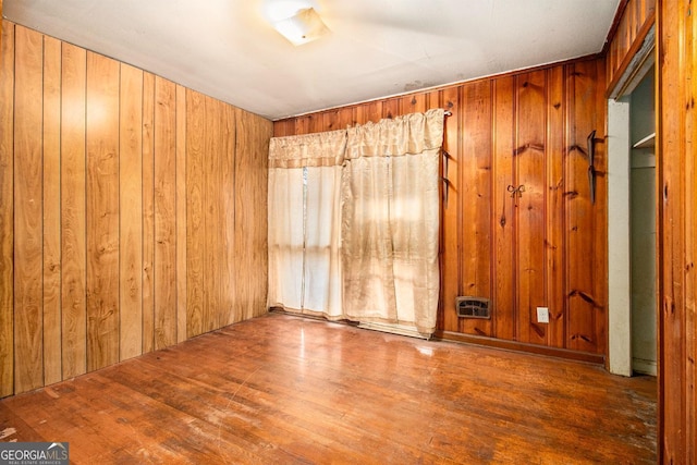 unfurnished room featuring hardwood / wood-style flooring and wood walls