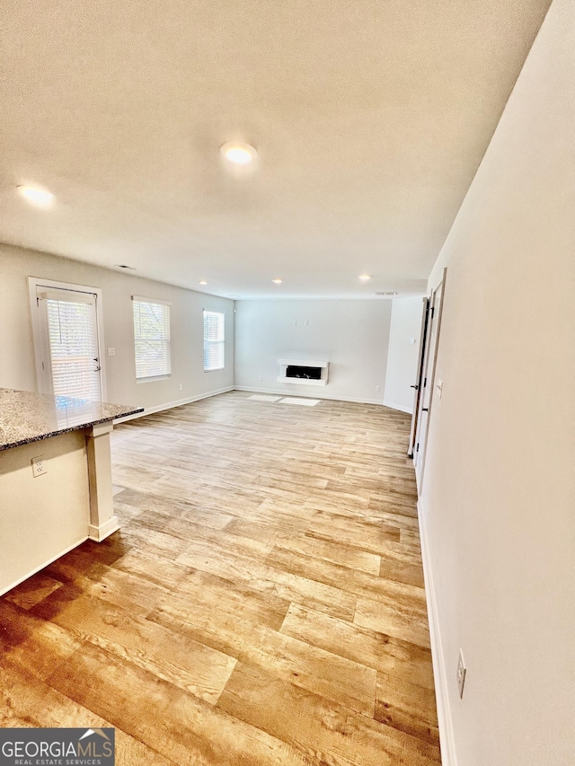 unfurnished living room featuring hardwood / wood-style flooring and a textured ceiling