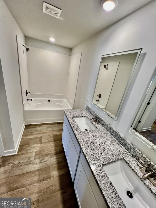 bathroom with a washtub, hardwood / wood-style flooring, and vanity