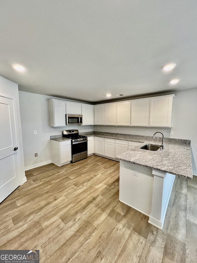 kitchen with sink, white cabinetry, appliances with stainless steel finishes, and kitchen peninsula