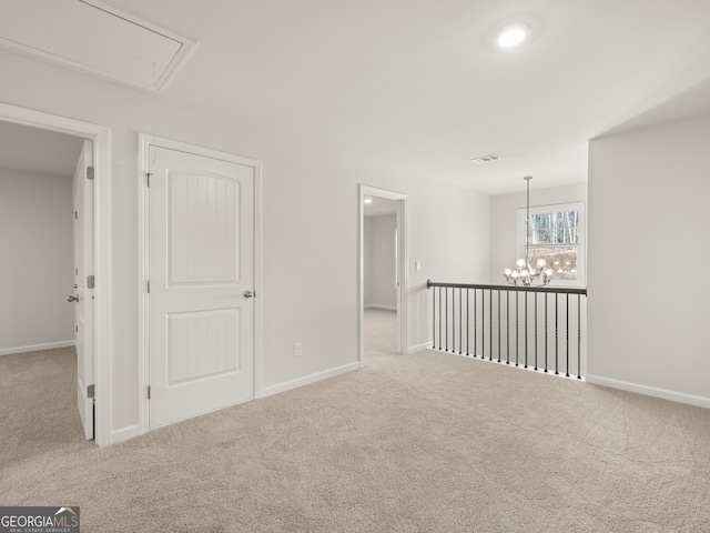 empty room with light carpet and a notable chandelier
