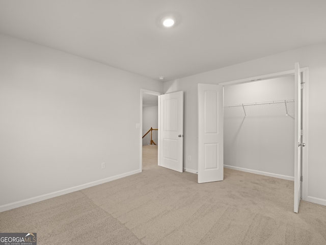 unfurnished bedroom with a closet and light carpet