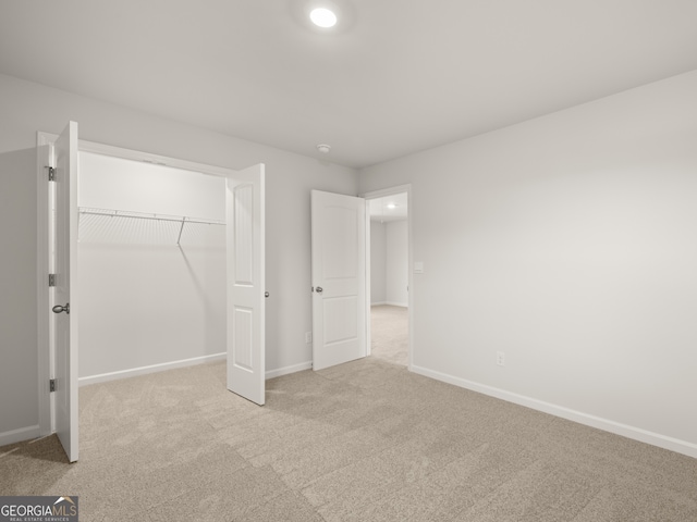 unfurnished bedroom with light colored carpet and a closet