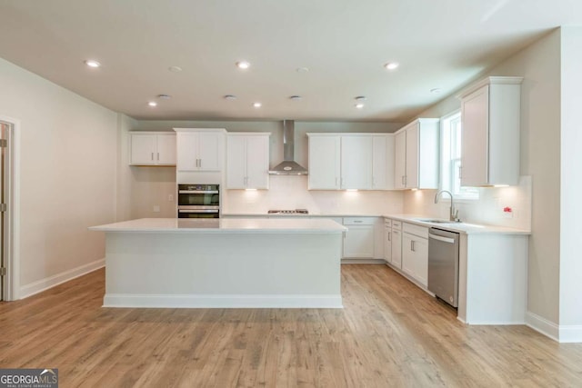 kitchen featuring wall chimney exhaust hood, sink, white cabinetry, a center island, and stainless steel appliances