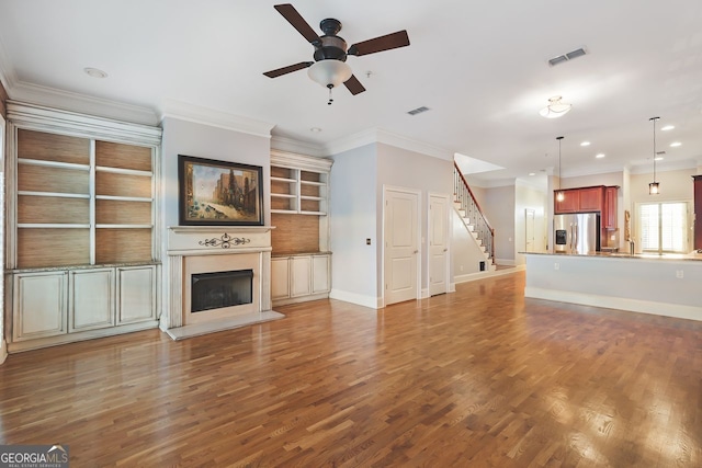 unfurnished living room with ceiling fan, ornamental molding, and hardwood / wood-style floors