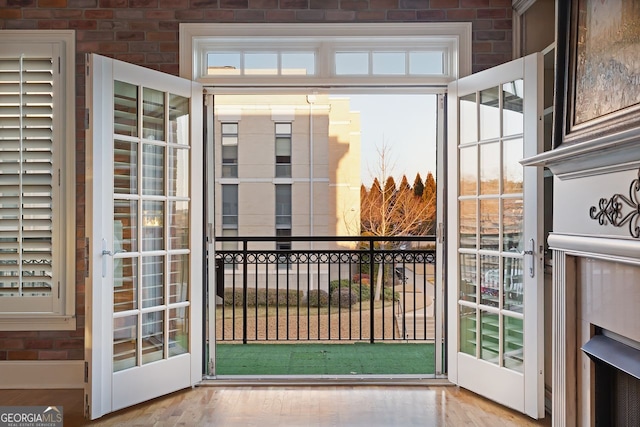 doorway to outside featuring brick wall and light wood-type flooring