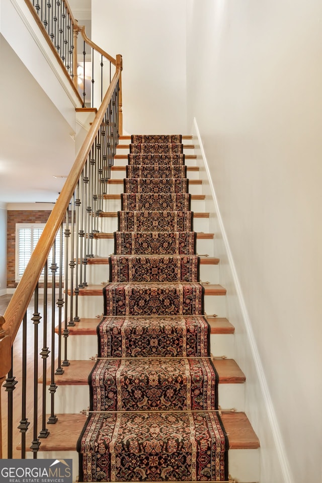 stairway with hardwood / wood-style flooring and a towering ceiling