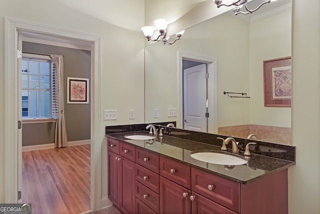 bathroom featuring vanity, hardwood / wood-style flooring, crown molding, and an inviting chandelier