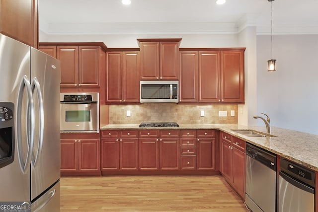 kitchen featuring sink, crown molding, light stone counters, decorative light fixtures, and stainless steel appliances