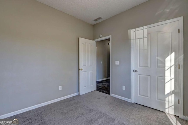 unfurnished bedroom featuring light colored carpet, a textured ceiling, and a closet