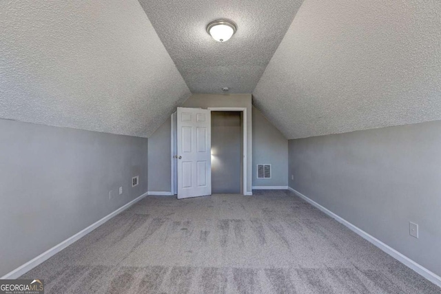 bonus room featuring light colored carpet, a textured ceiling, and lofted ceiling