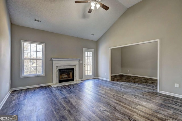 unfurnished living room featuring vaulted ceiling, a healthy amount of sunlight, dark wood-type flooring, and a fireplace