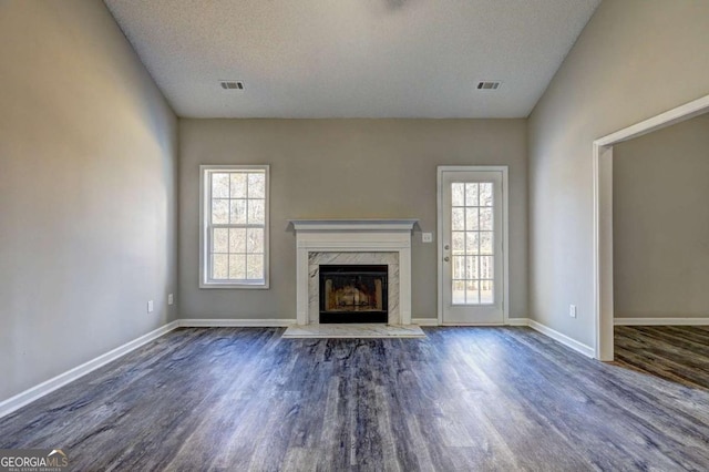 unfurnished living room featuring a high end fireplace, dark hardwood / wood-style floors, and a textured ceiling