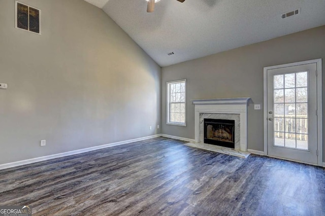 unfurnished living room featuring a healthy amount of sunlight, a textured ceiling, dark hardwood / wood-style floors, and vaulted ceiling