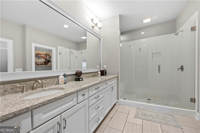 bathroom with a shower with shower door and vanity